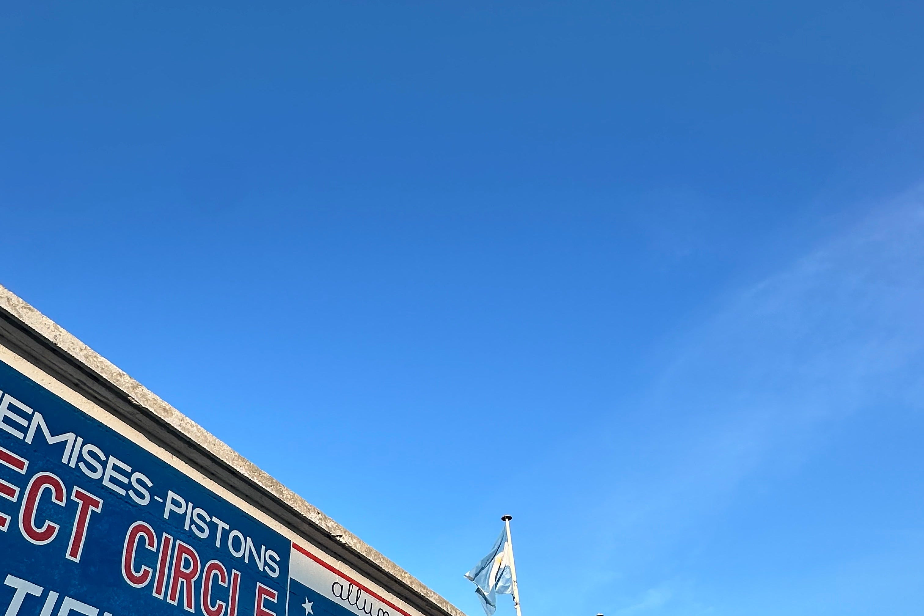Stadium seating with advertisements and flags against a blue sky at the iconic reims raceway